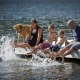 Dog and family on a dock with their feet splashing in the water