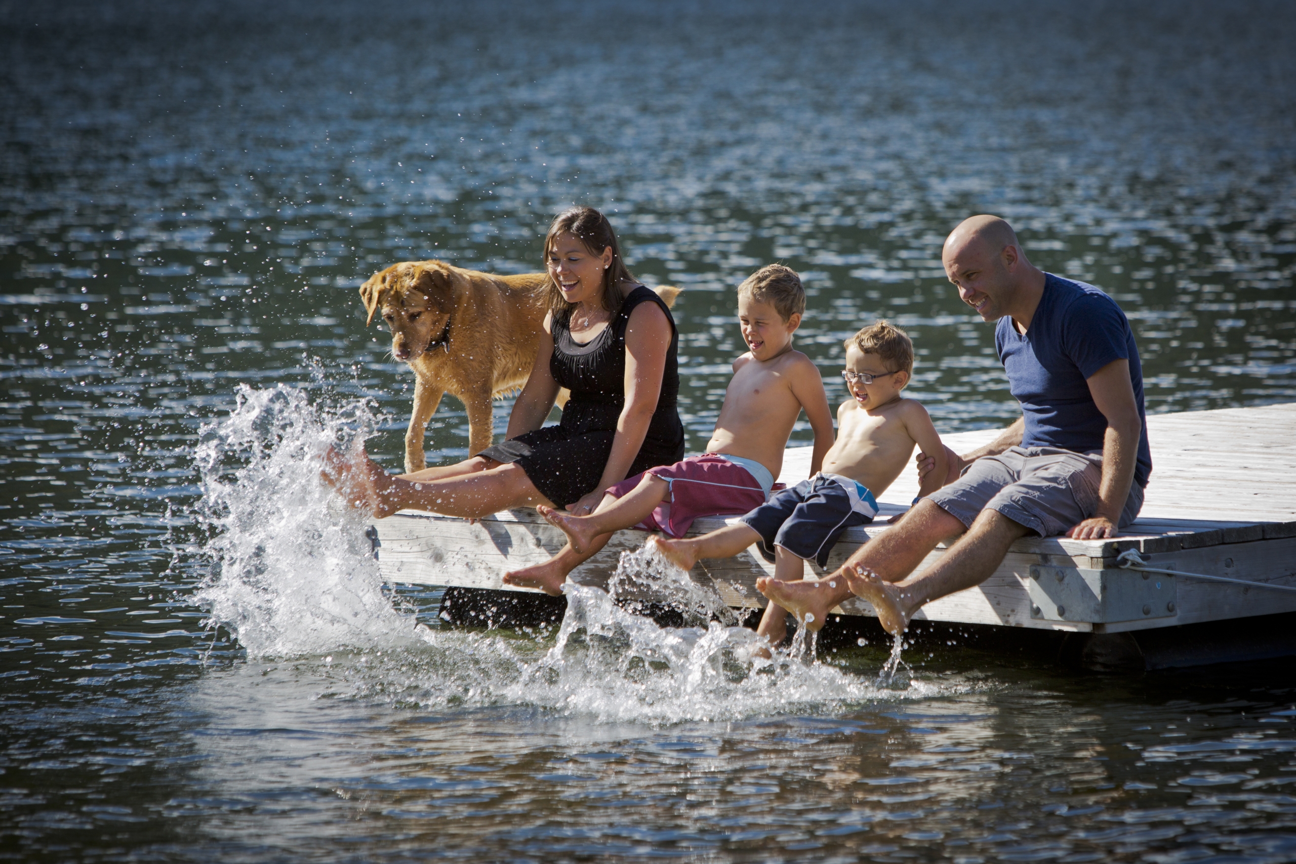 Dog and family on a dock with their feet splashing in the water