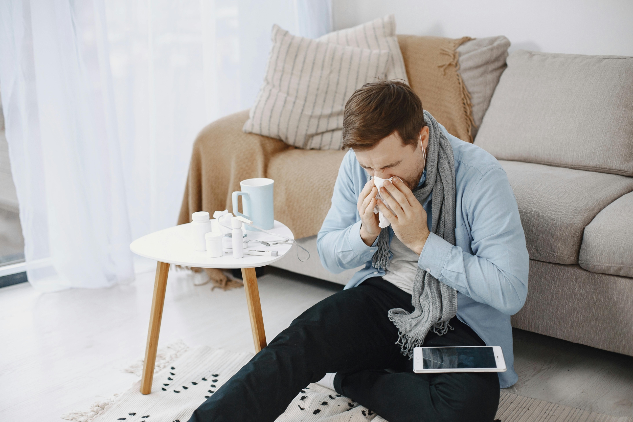 Man sneezing beside his allergy medications in Arkansas home